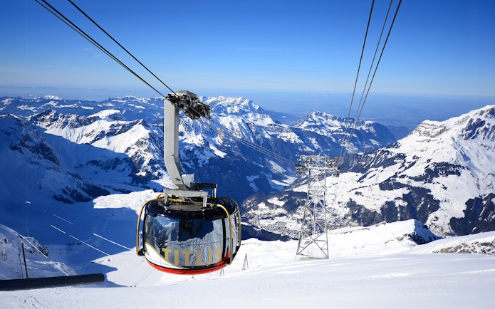 Titlis Rotair cablecar ascending over snowy Swiss Alps.