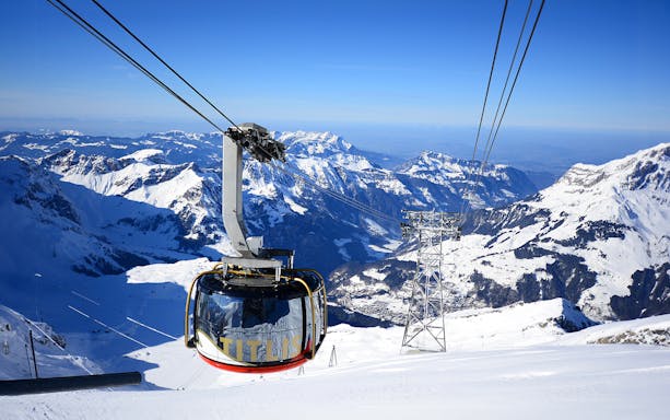 Titlis Rotair cablecar ascending over snowy Swiss Alps.