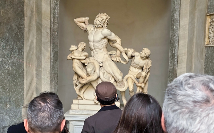 Visitors viewing Laocoön and His Sons sculpture at Vatican Museums.