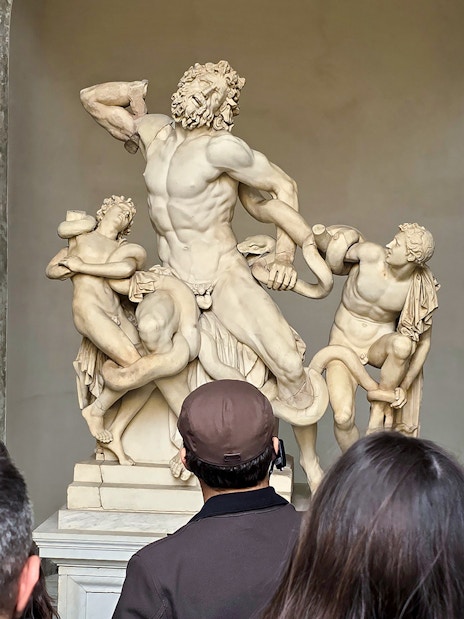 Visitors viewing Laocoön and His Sons sculpture at Vatican Museums.