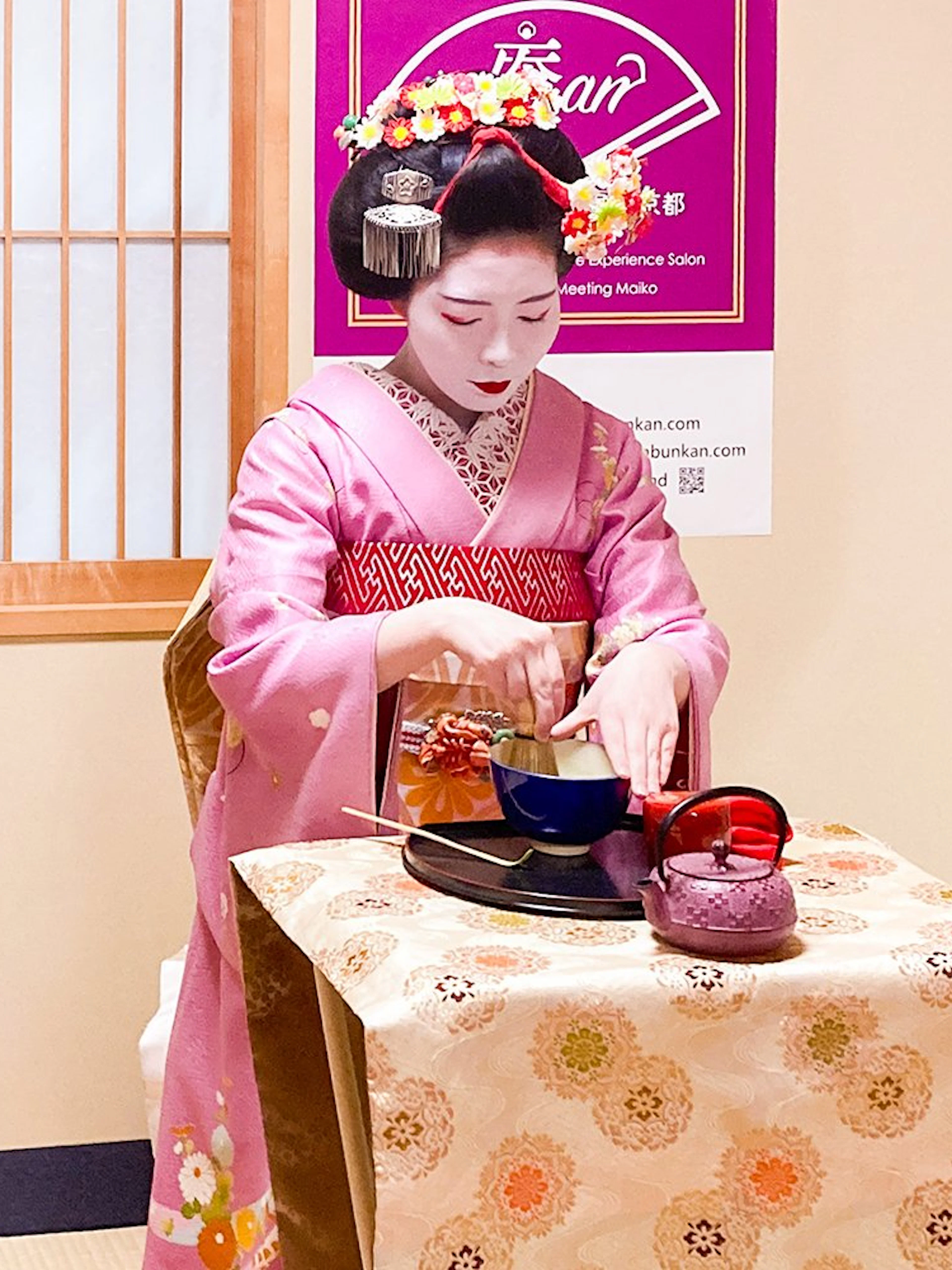 Maiko performing tea ceremony in traditional attire during cultural experience in Kyoto.