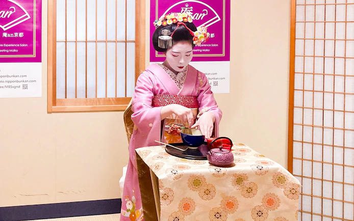 Maiko performing tea ceremony in traditional attire during cultural experience in Kyoto.