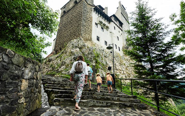 Tourists with children walking up steps to Bran Castle, Romania.