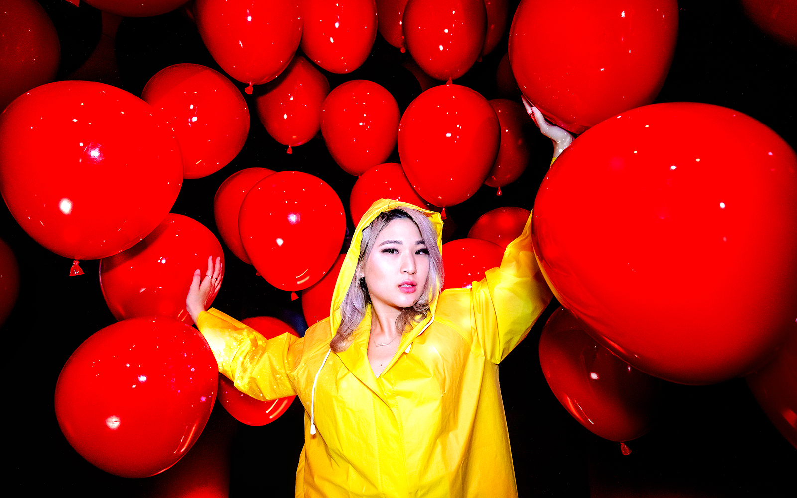 Guest in yellow raincoat surrounded by red balloons at Madame Tussauds Hollywood.