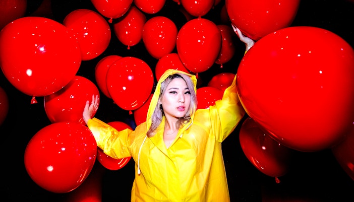 Guest in yellow raincoat surrounded by red balloons at Madame Tussauds Hollywood.