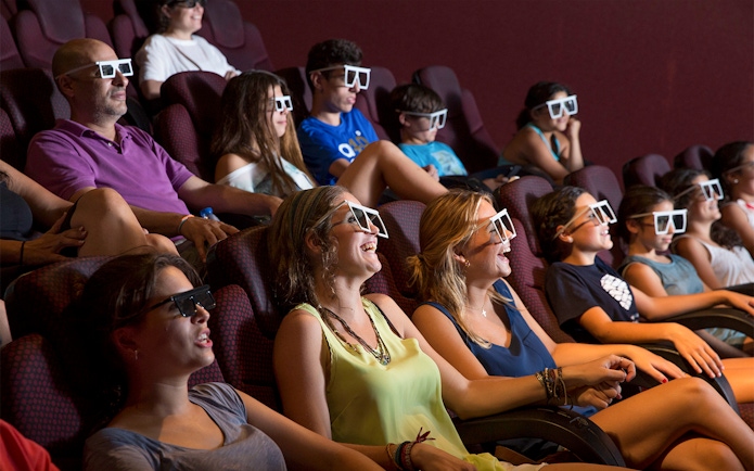 Visitors enjoying a 4D cinema experience at Isla Magica, wearing 3D glasses.