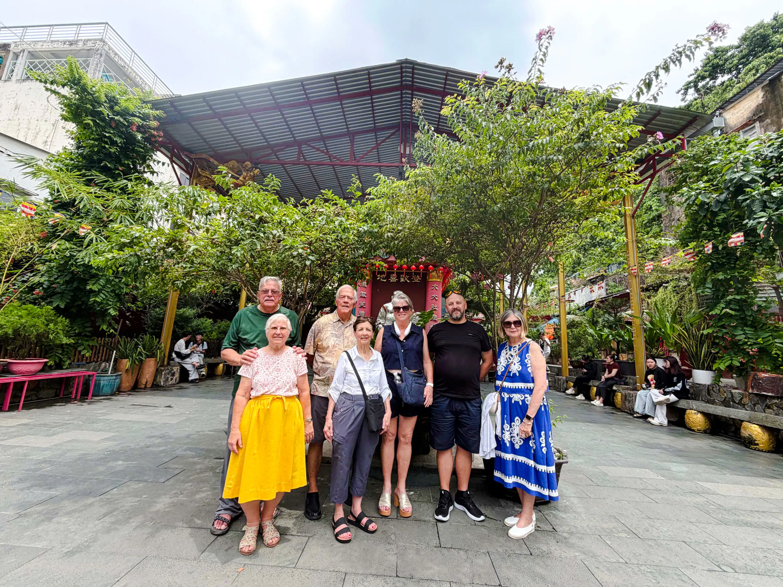 Group of tourists at a historic site in Ho Chi Minh City, surrounded by greenery and traditional architecture.