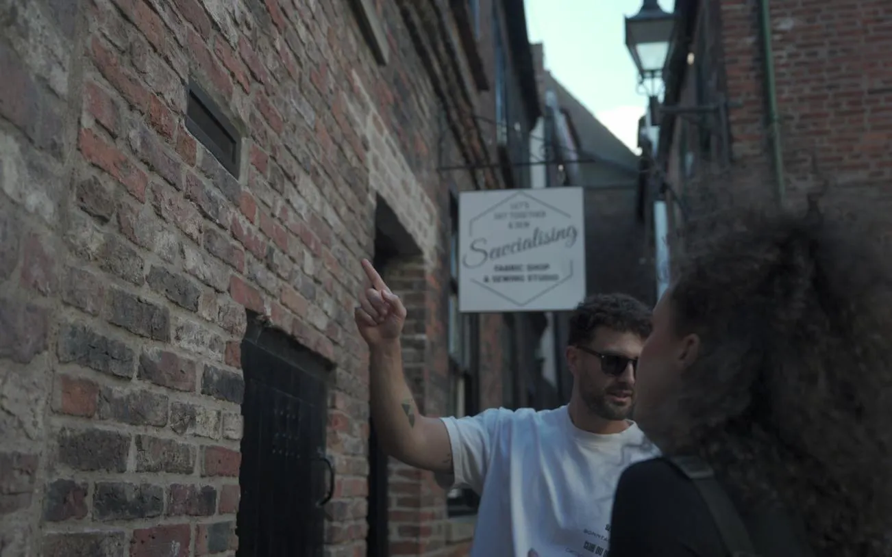 Man pointing at a clue on a brick wall during York outdoor escape room adventure game.