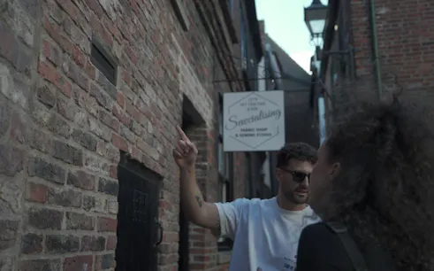 Man pointing at a clue on a brick wall during York outdoor escape room adventure game.