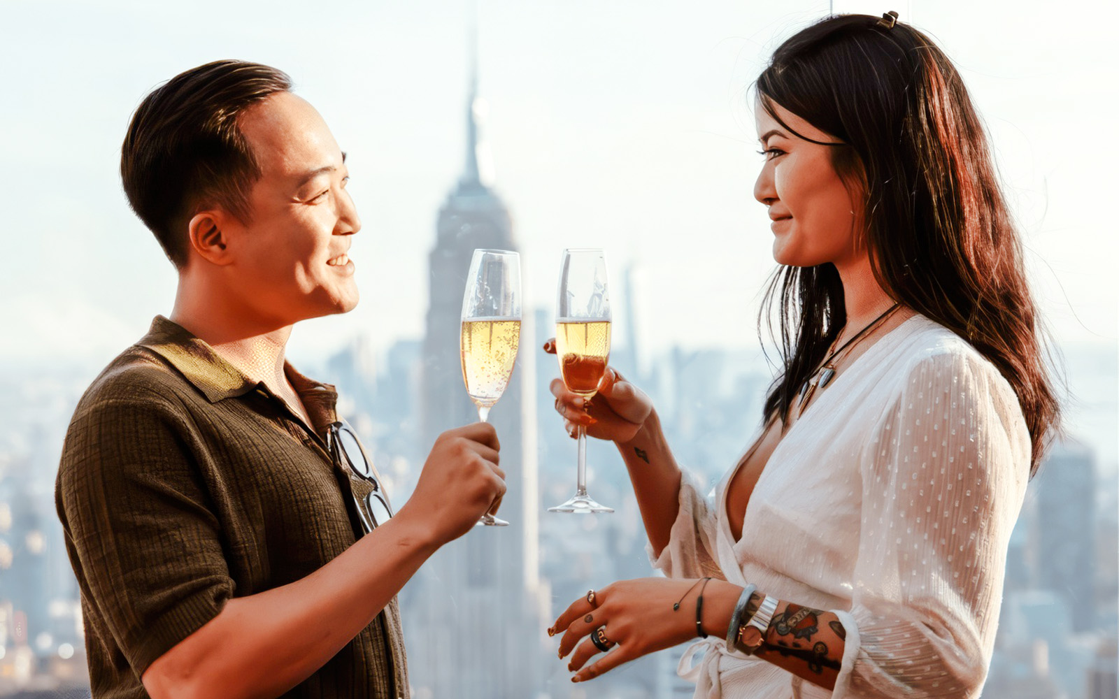Couple toasting with champagne at Top of the Rock, New York City skyline in background.
