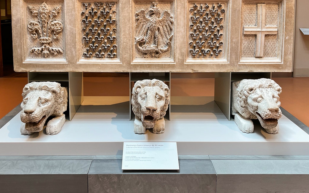 Stone lion sculptures and ornate carvings at Florence Duomo museum exhibit.