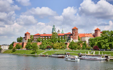 Krakow's Wawel Castle viewed from the Vistula River with sightseeing boats.