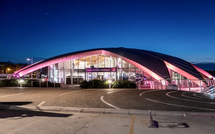 Malta National Aquarium illuminated at dusk with a clear sky.
