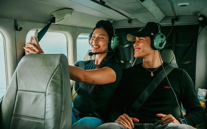 Couple enjoying a scenic Kauai helicopter tour with headsets on.