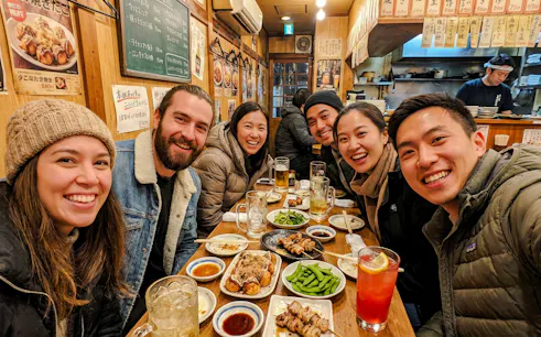 Group enjoying food and drinks at an Osaka eatery during a food tour.