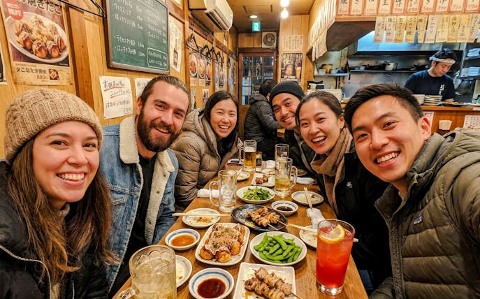 Group enjoying food and drinks at an Osaka eatery during a food tour.
