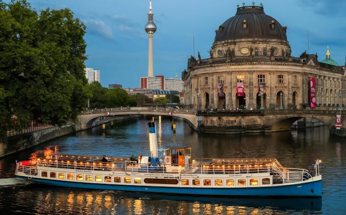 Evening cruise boat passing Bode Museum on Museum Island, Berlin, with TV Tower in background.