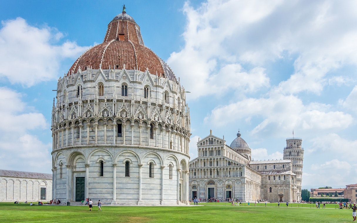 Baptistry of San Giovanni exterior with Pisa Cathedral and Leaning Tower in background.