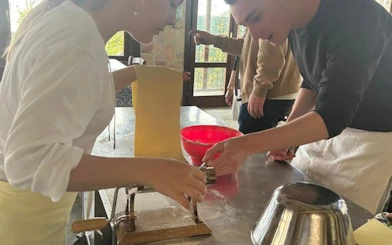 Pasta making at Amalfi Coast farmhouse cooking class with participants using pasta machine.