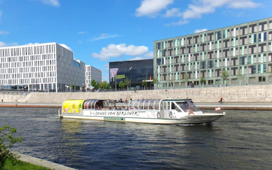 Tour boat cruising on the Spree River in Berlin with modern buildings in the background.