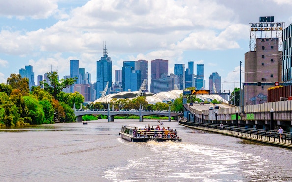 Cruise boat on Yarra River with Melbourne skyline in the background.
