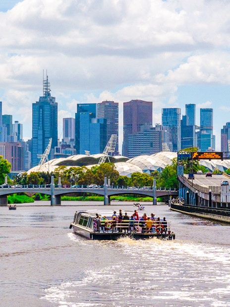 Cruise boat on Yarra River with Melbourne skyline in the background.