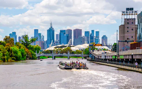 Cruise boat on Yarra River with Melbourne skyline in the background.