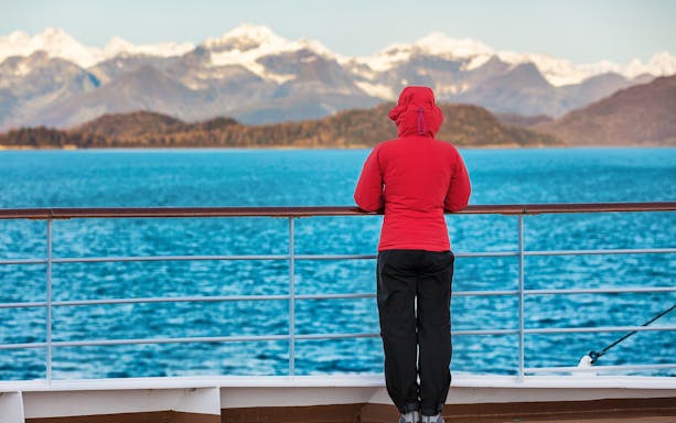 Person in red jacket on cruise ship deck with view of mountains and lake during Lugano and Bellagio tour.