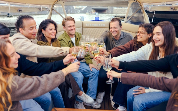 Guests toasting on a covered canal cruise in Amsterdam.