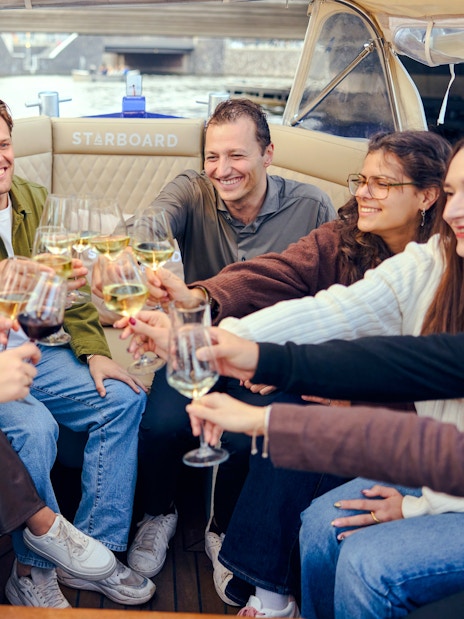Guests toasting on a covered canal cruise in Amsterdam.
