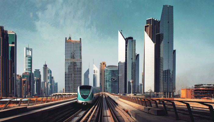 Dubai metro train approaching city skyline with modern skyscrapers.