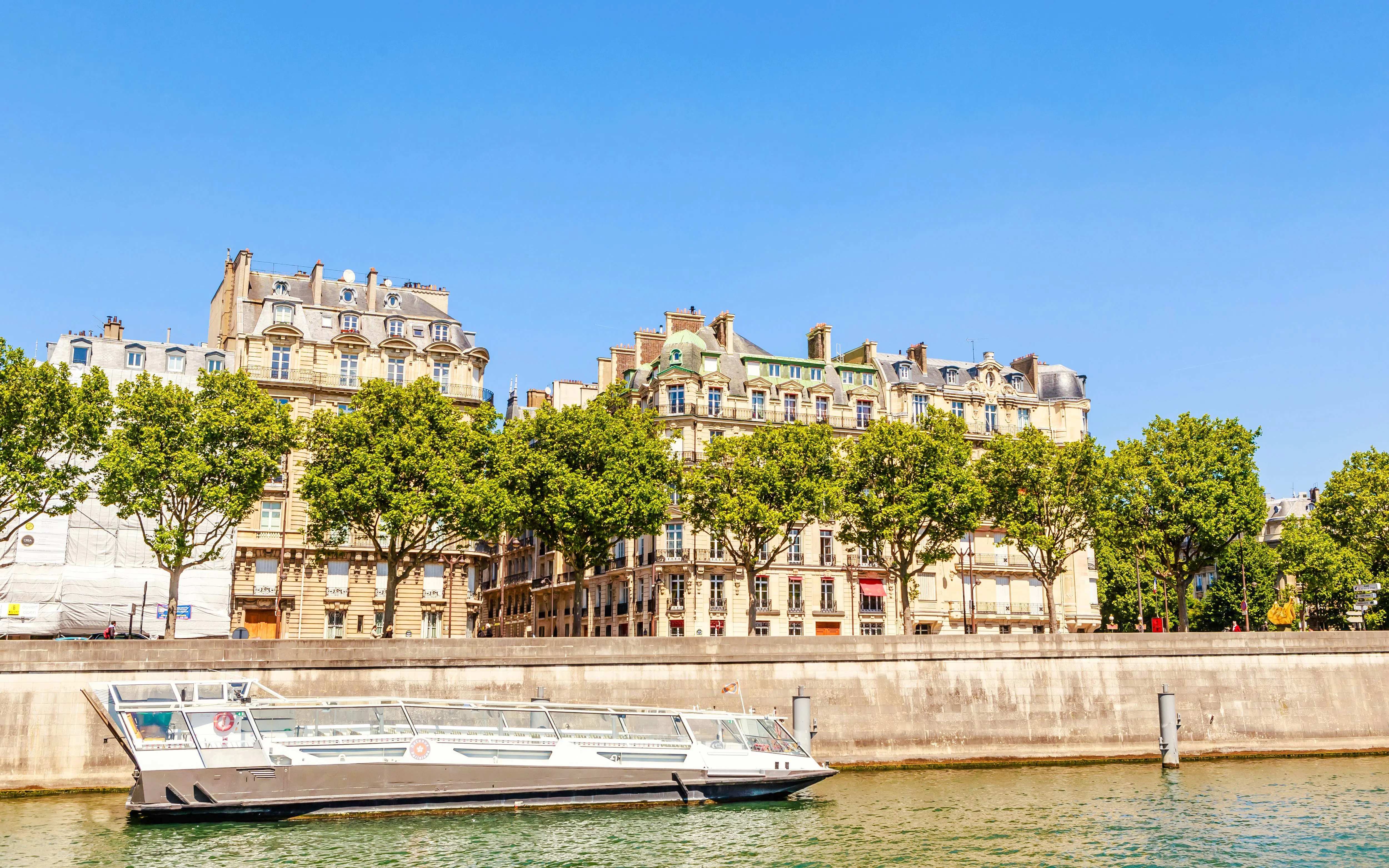 Tour boat on the Seine River near Port de la Conférence, Paris, with historic buildings in the background.