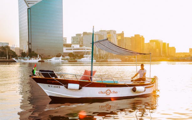 Boat on Dubai Creek with modern skyscrapers in the background during the New Dubai Skyscrapers Tour.
