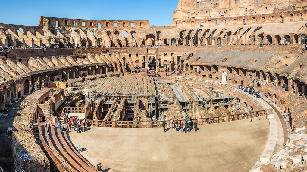 Colosseum interior with tourists exploring ancient amphitheater in Rome, Italy.