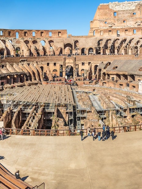 Colosseum interior with tourists exploring ancient amphitheater in Rome, Italy.