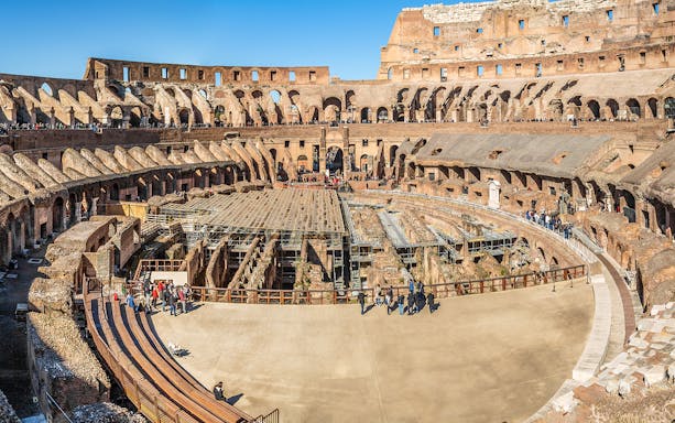 Colosseum interior with tourists exploring ancient amphitheater in Rome, Italy.