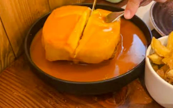 Francesinha sandwich with sauce and fries on Lisbon vegan food tour.