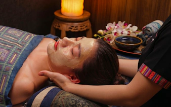 Facial treatment at Herbal Spa in Da Nang with orchids and warm lighting.