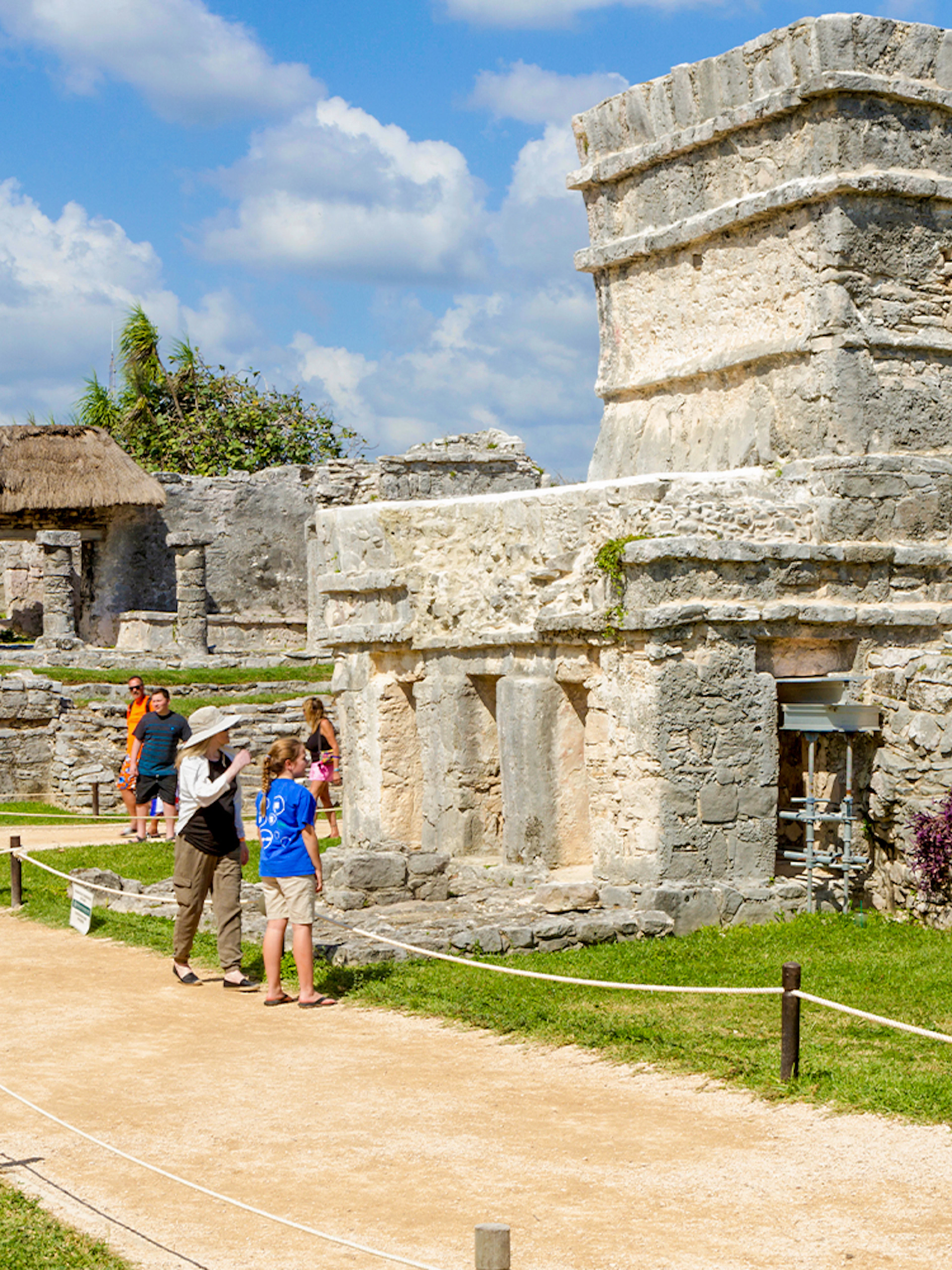 Tourists walking among ancient stone structures at Chichen Itza, Mexico.