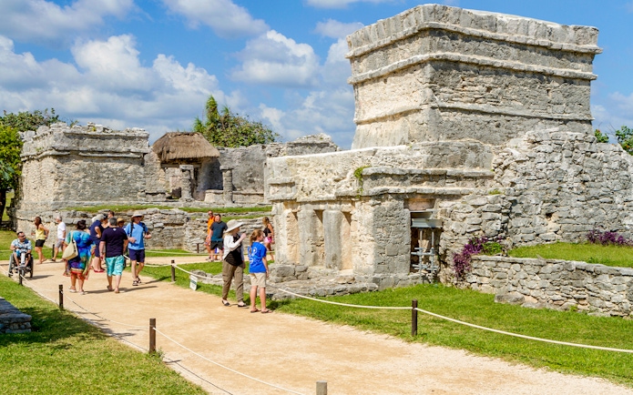 Tourists walking among ancient stone structures at Chichen Itza, Mexico.