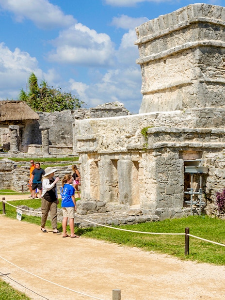 Tourists walking among ancient stone structures at Chichen Itza, Mexico.