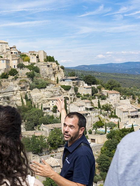 Tour guide explaining the view of Gordes village in Provence to visitors.