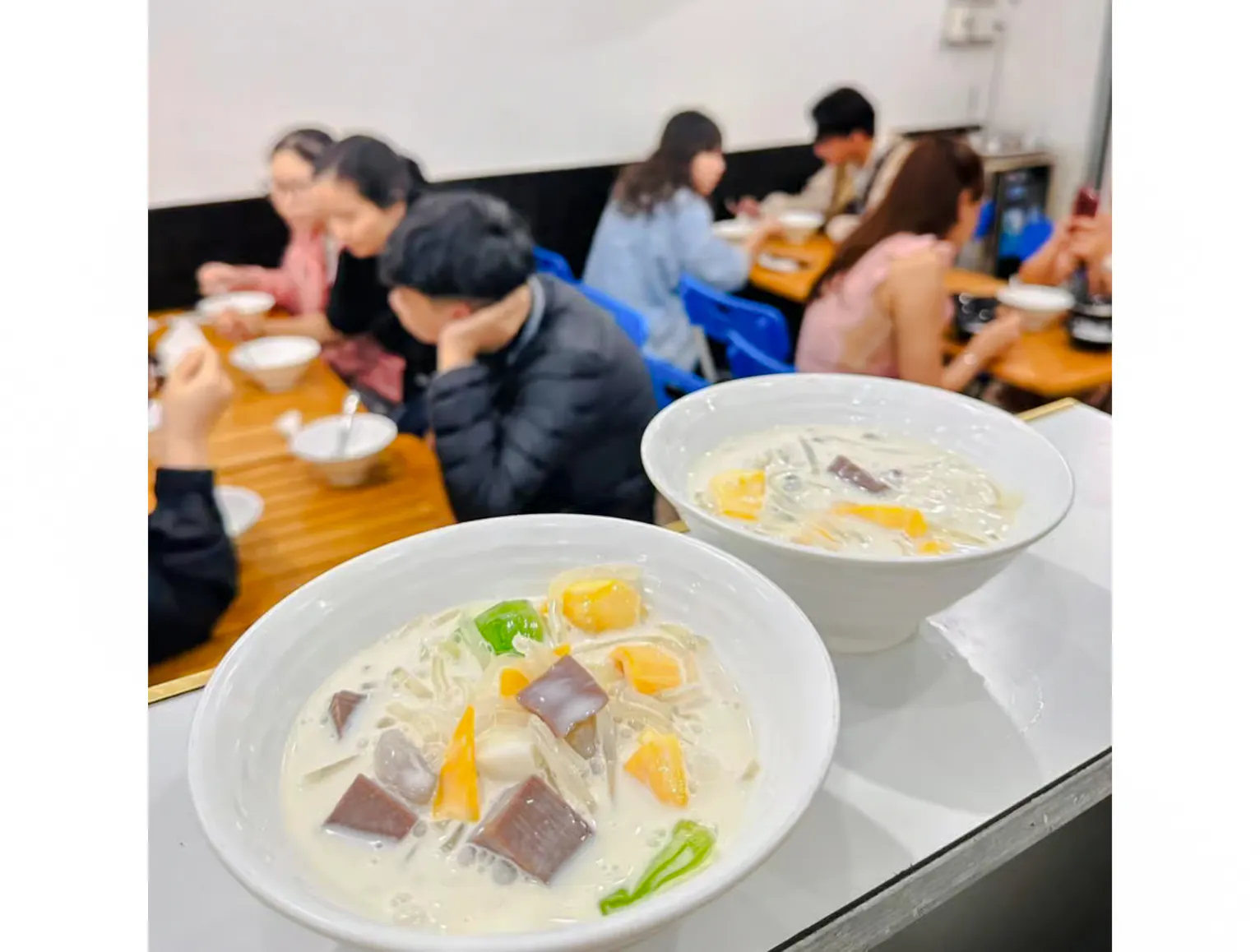 Bowls of Vietnamese dessert soup on a table with people dining in Da Nang.