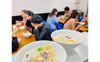 Bowls of Vietnamese dessert soup on a table with people dining in Da Nang.