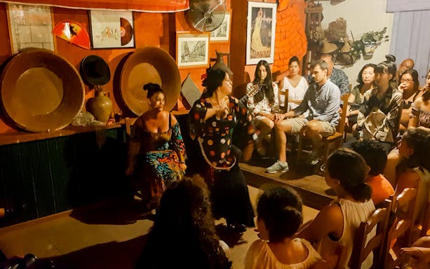 Flamenco dancer performing in a cozy venue in Triana, surrounded by an audience.