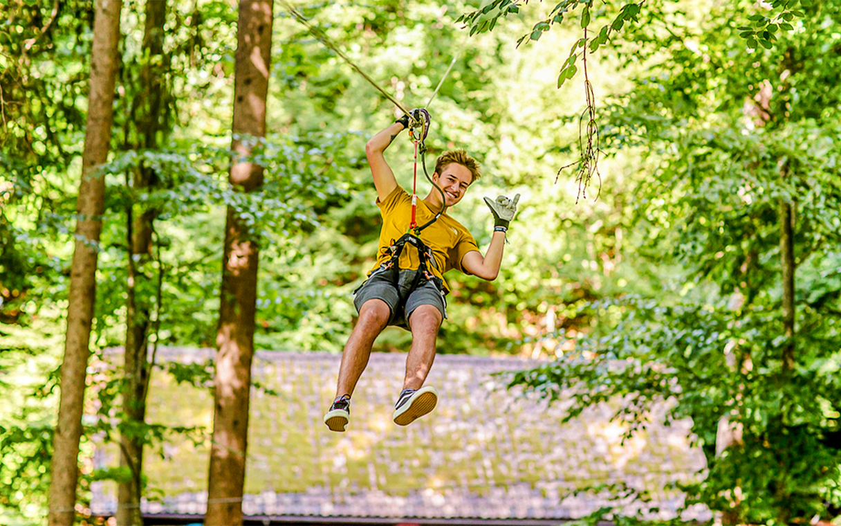 Person ziplining through trees at Ropes Park Interlaken.