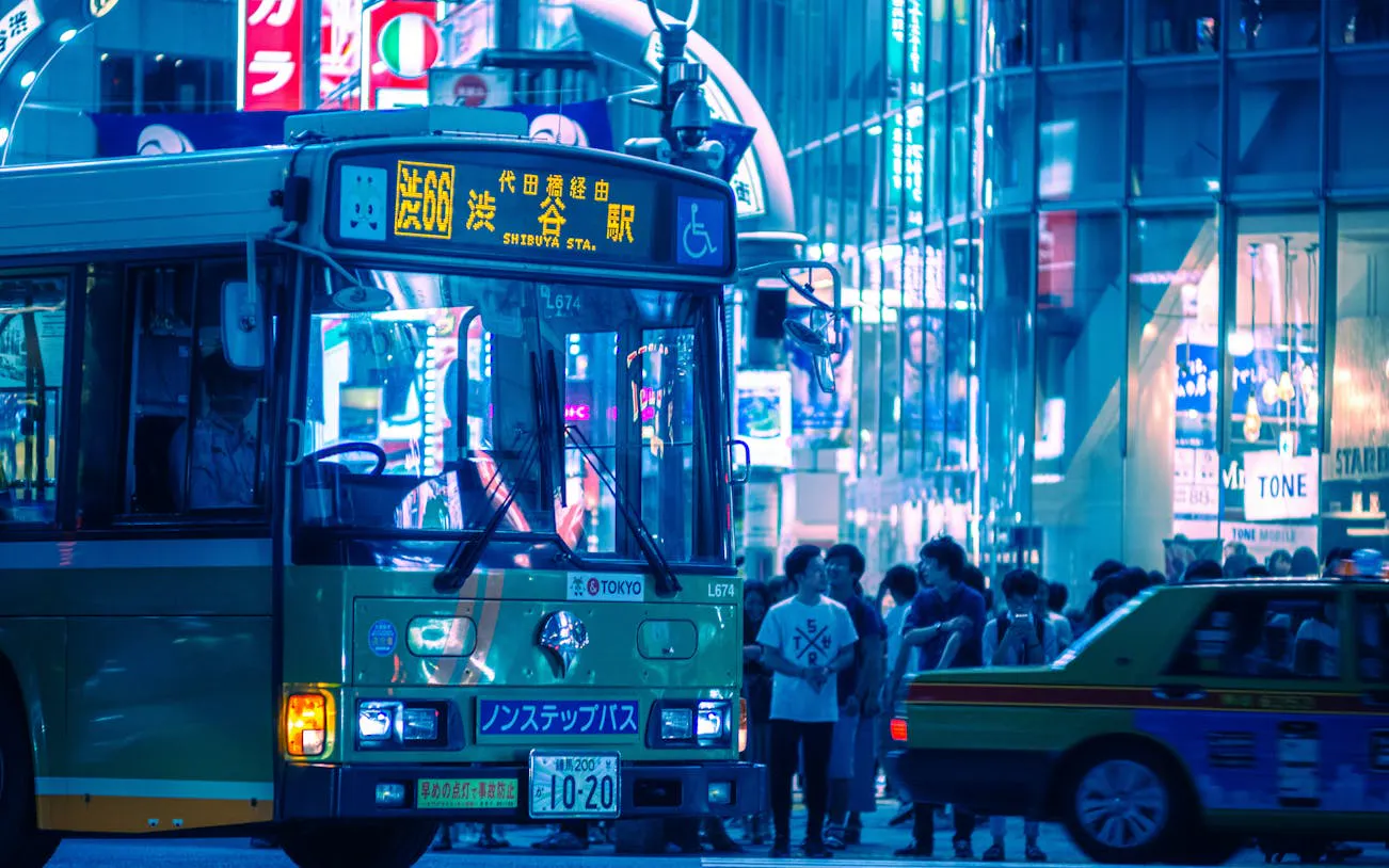 Tokyo Shibuya night scene with bus and crowd near Scramble Crossing.
