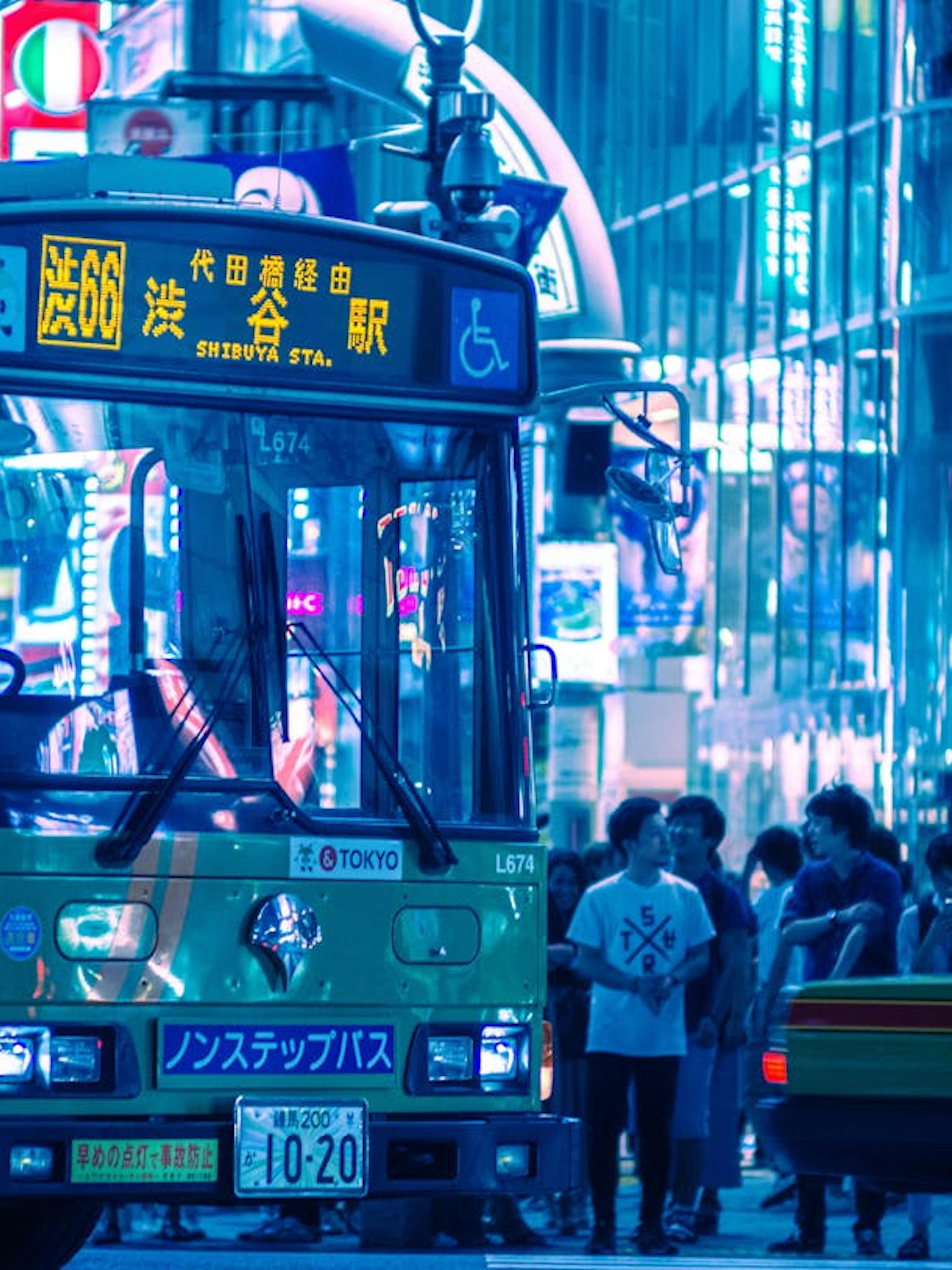 Tokyo Shibuya night scene with bus and crowd near Scramble Crossing.