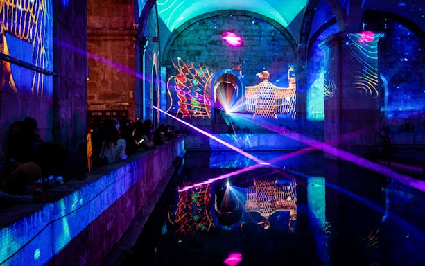 Light show with Egyptian motifs at Misterioso Egito in Lisbon, featuring colorful projections and reflections.