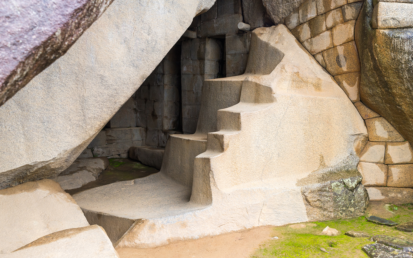 Ancient stone steps at Machu Picchu, Peru, leading into a carved rock chamber.